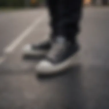 Close-up of all black Converse with skateboarding surface